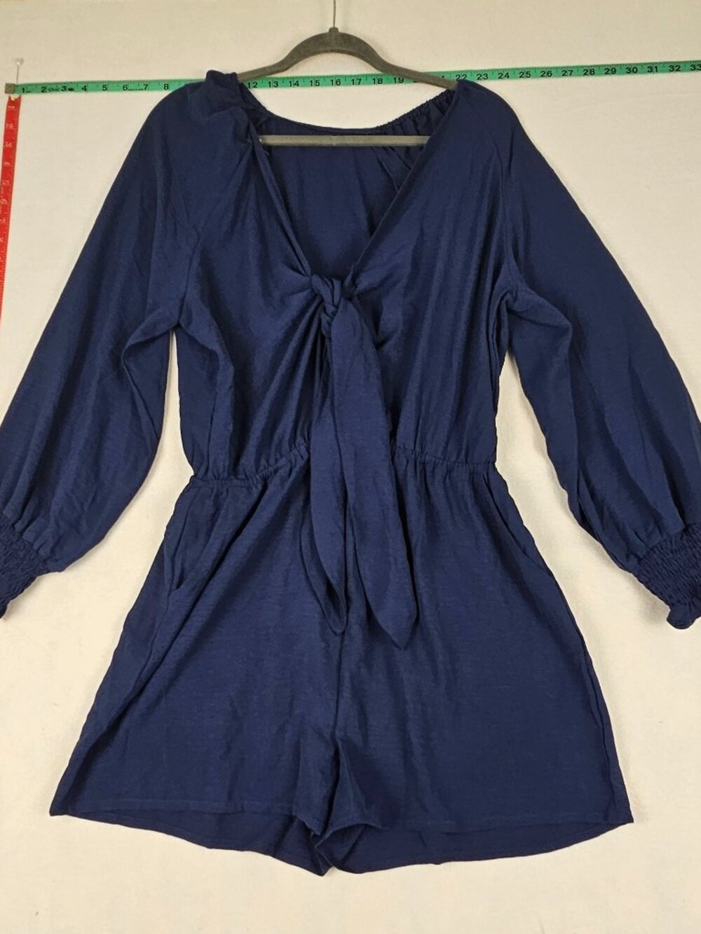 This Long Sleeve blue jumpsuit/romper size Lg with deep V-neck and front tie/bow